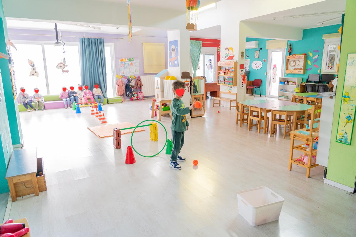 Παιδιά που συμμετέχουν σε κινητικά παιχνίδια και δραστηριότητες σε μεγάλη αίθουσα του σταθμού.